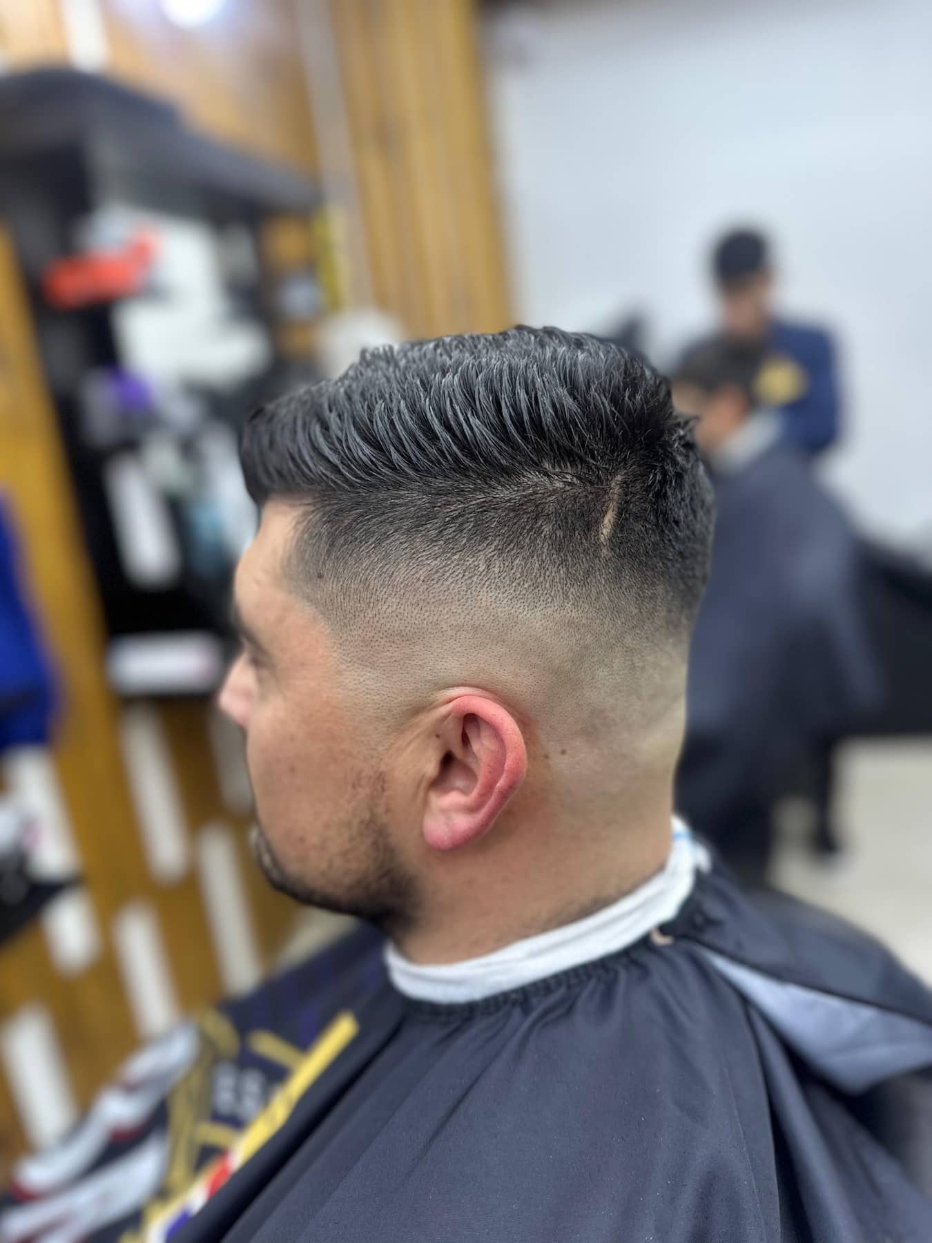 Cliente de perfil con un fade alto y el pelo texturizado, recién cortado en Barbería Montt
